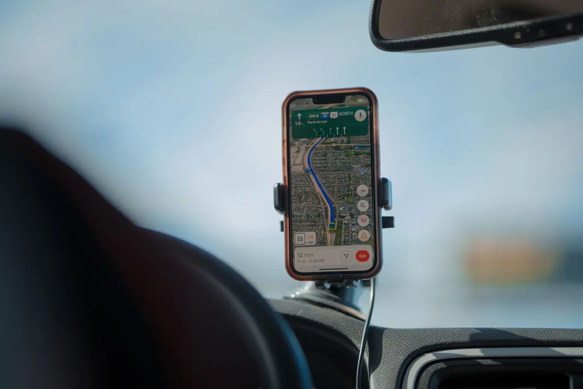 Smartphone showing a map navigation app in a mount on a car dashboard during a road trip